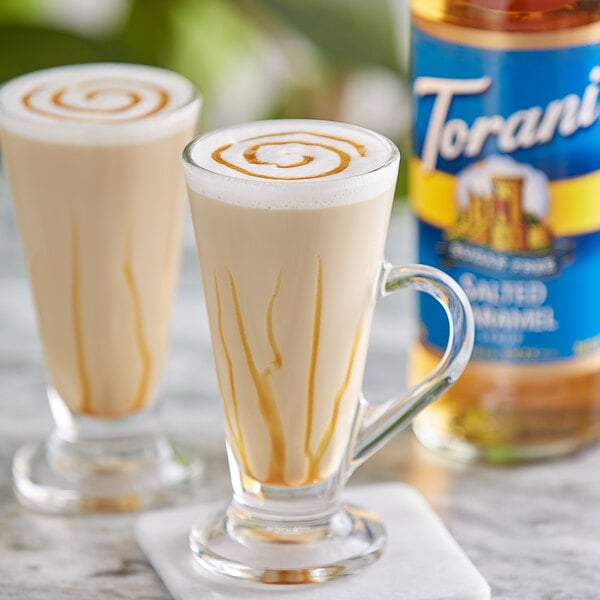 Two glasses of coffee with Torani Sugar-Free Salted Caramel syrup in it and caramel sauce swirls on top.