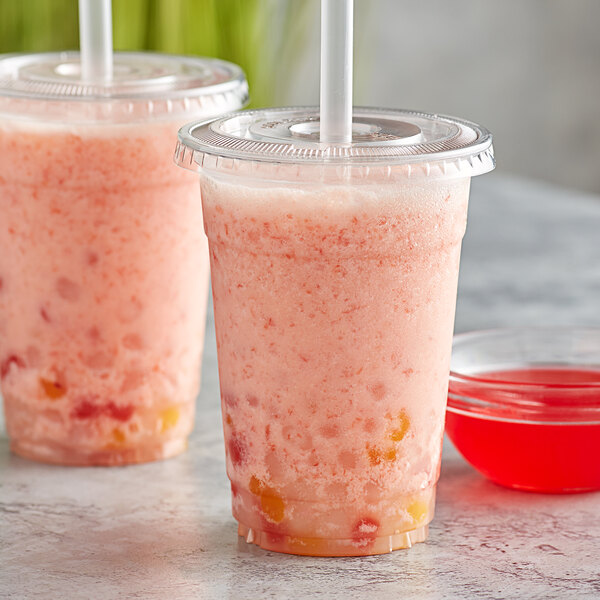 A bowl of red Bossen guava syrup next to two plastic cups of pink drinks with straws.