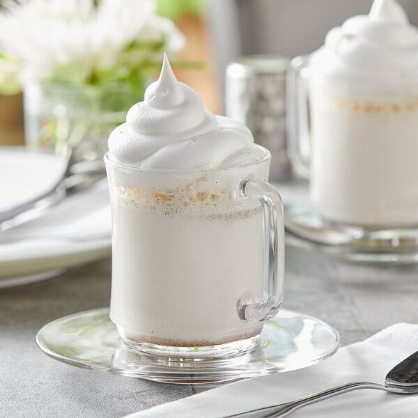 A glass mug of Capora Vanilla Bean Frappe with whipped cream on top.