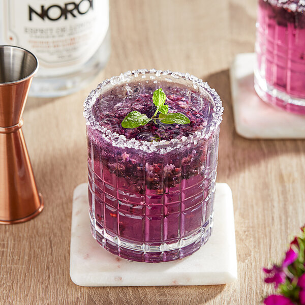 A glass of purple NOROI Esprit-de-London non-alcoholic gin with a sprig of mint.