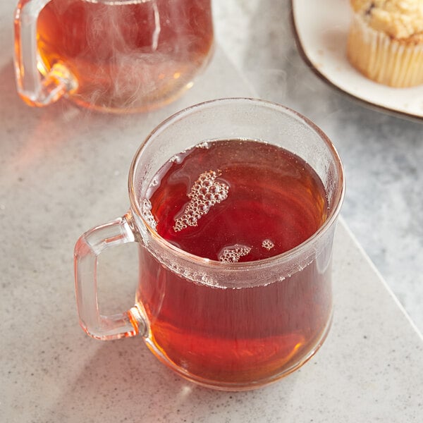 A glass mug of Twinings Irish Breakfast tea with a plate of muffins.