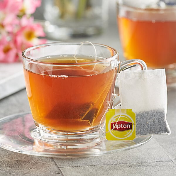 A glass cup of Lipton Spiced Chai Black Tea with a tea bag in it.