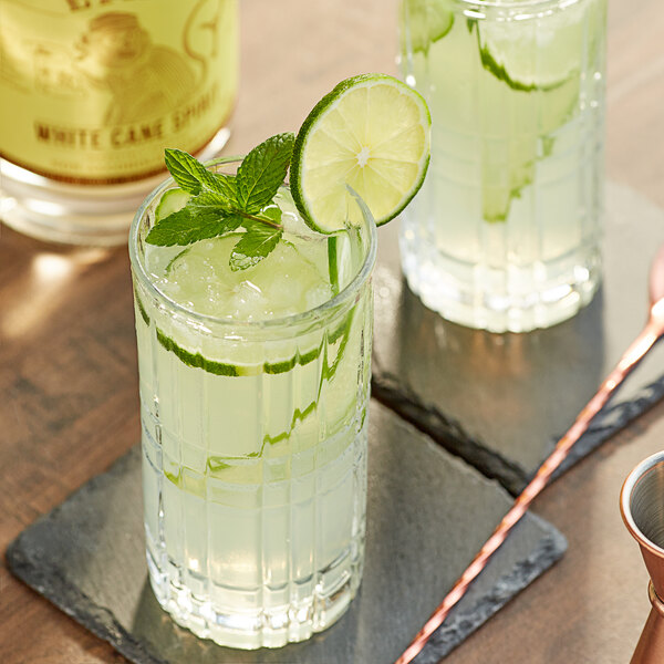 A glass of Lyre's White Cane Spirit with a lime slice and mint leaves.