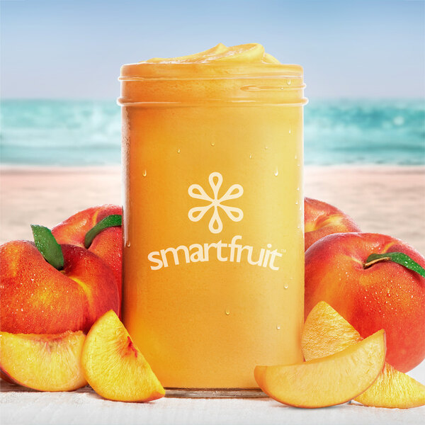 A glass jar of Smartfruit Perfect Peach smoothie with peaches on top.
