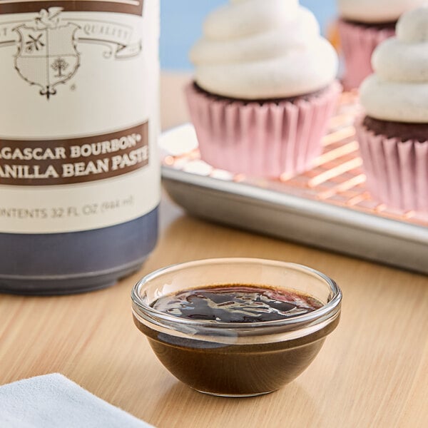 A cupcake with white frosting and Madagascar Bourbon vanilla paste on a table.