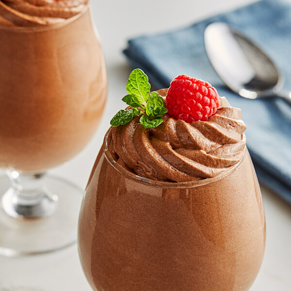 A chocolate mousse with a raspberry on top in a glass.