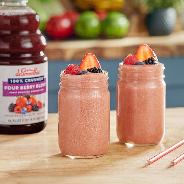 Two glasses of pink Dr. Smoothie Four Berry smoothie with straws on a counter.