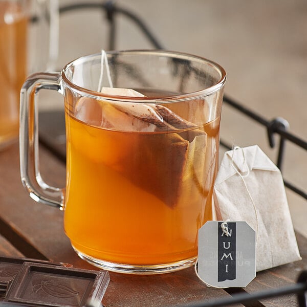 A glass mug of Numi Organic Chocolate Rooibos tea with a tea bag.