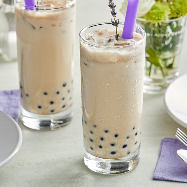 Two glasses of Fanale lavender bubble tea with purple straws on a white background.