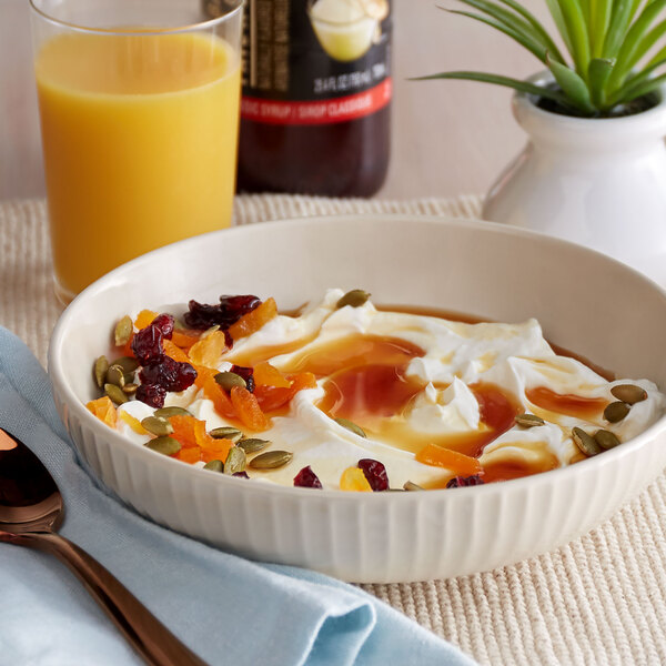 A bowl of yogurt with fruit and nuts next to a DaVinci Gourmet Classic Cake Batter Flavoring Syrup bottle.