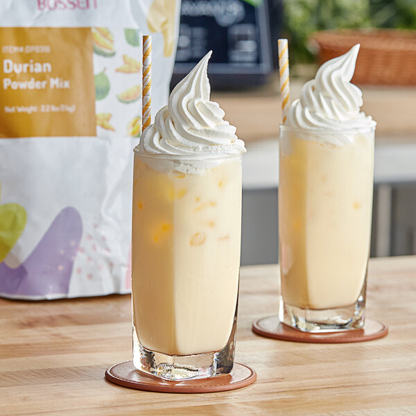 Two glasses of durian milkshakes with whipped cream on top.