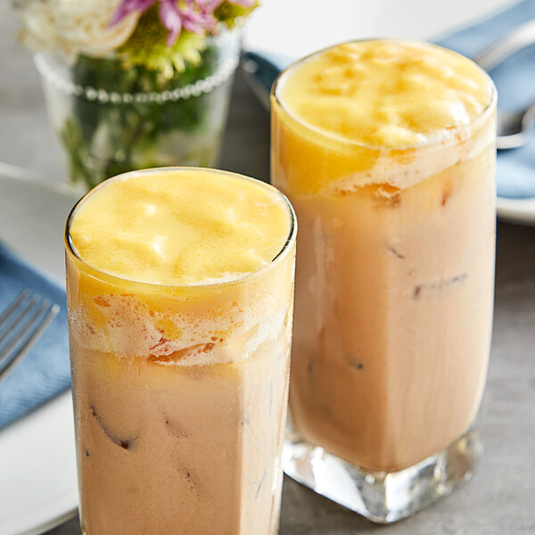 Two glasses of yellow Fanale egg pudding on a table with a blue cloth