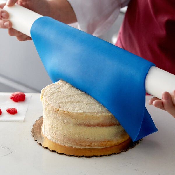 A person using Satin Ice ChocoPan blue covering chocolate to cover a cake.