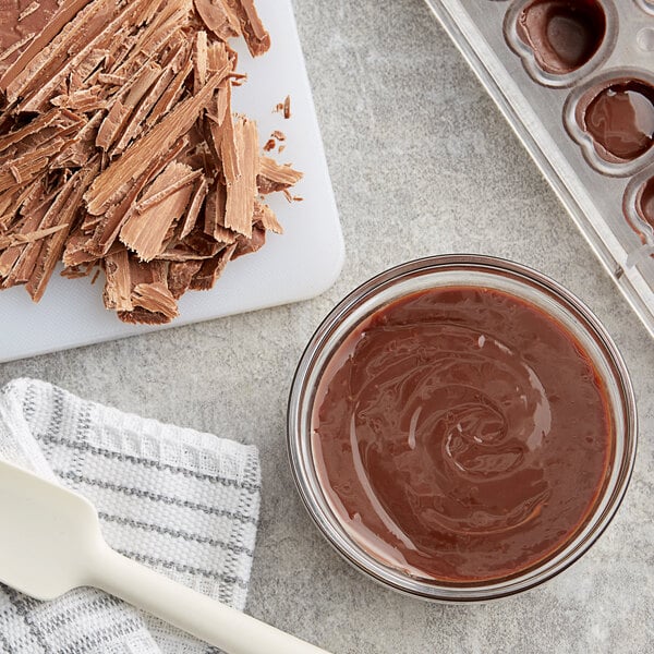 A bowl of melted Callebaut milk chocolate next to a white spatula.