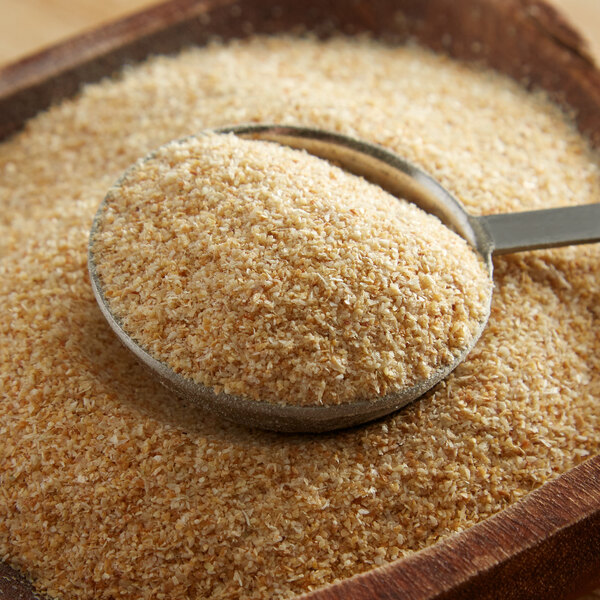 A spoonful of Regal granulated onion in a wooden bowl.