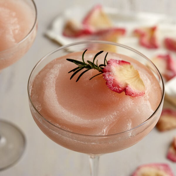 A glass of pink Finest Call Frose mix with a rose on top.