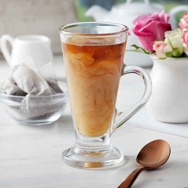 A glass cup of brown tea with a Bossen Rose Dark Oolong tea bag in it.