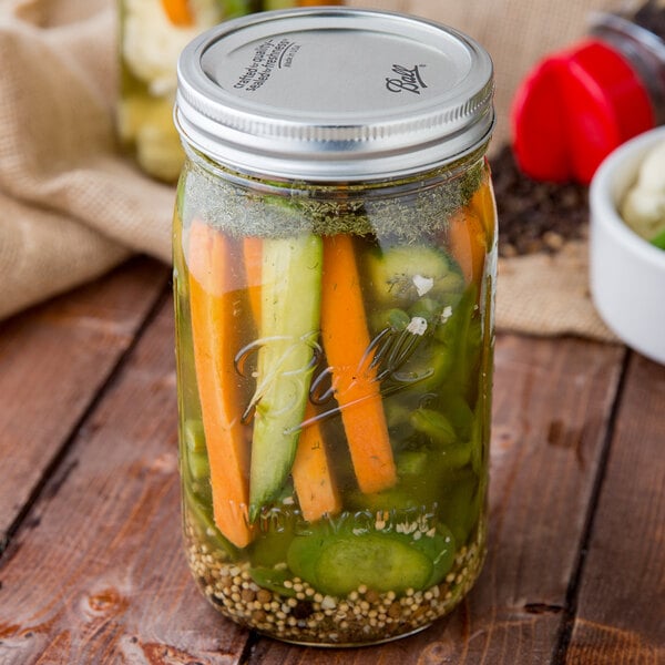 A case of 12 jars of Morton Coarse Kosher Salt on a counter filled with pickled vegetables.