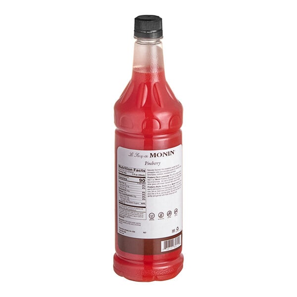 A Monin Premium Pineberry Flavoring Syrup bottle full of red liquid.