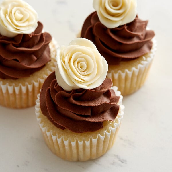 Three cupcakes with Satin Ice ChocoPan ivory modeling chocolate and white roses on top.