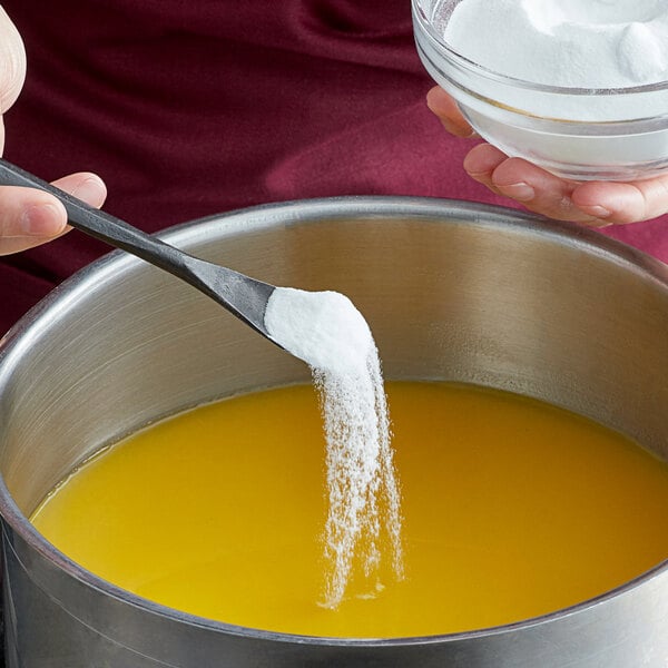 A spoon pouring Regal salt powder into a bowl of liquid.