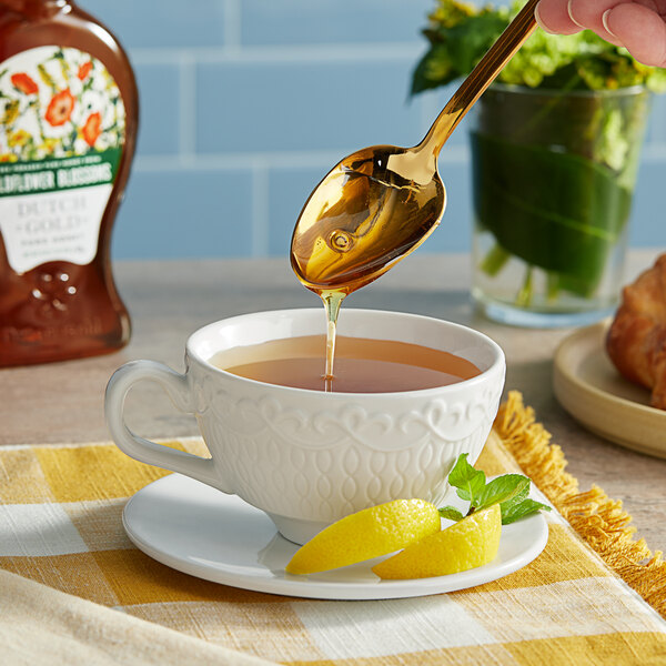A person pouring Dutch Gold wildflower honey into a cup of tea.