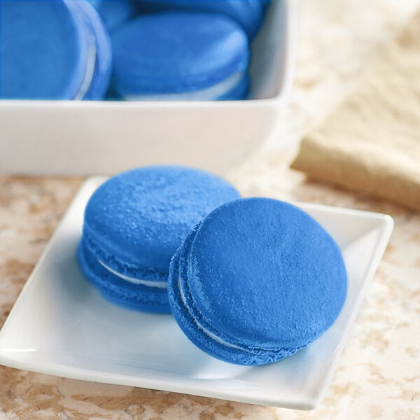 A white plate of blue macarons with white filling.