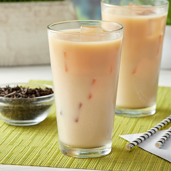 A glass of dark tea with ice on a white background.