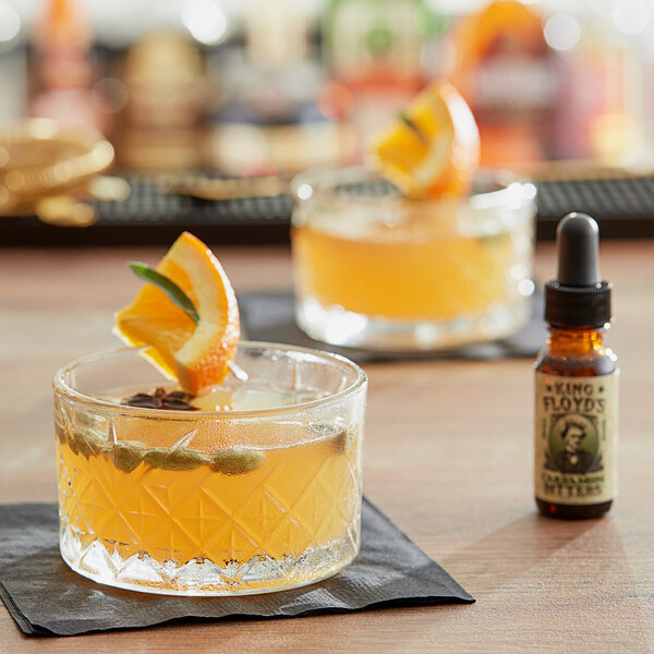 A glass of orange drink with King Floyd's Cardamom Bitters and an orange slice on the rim.