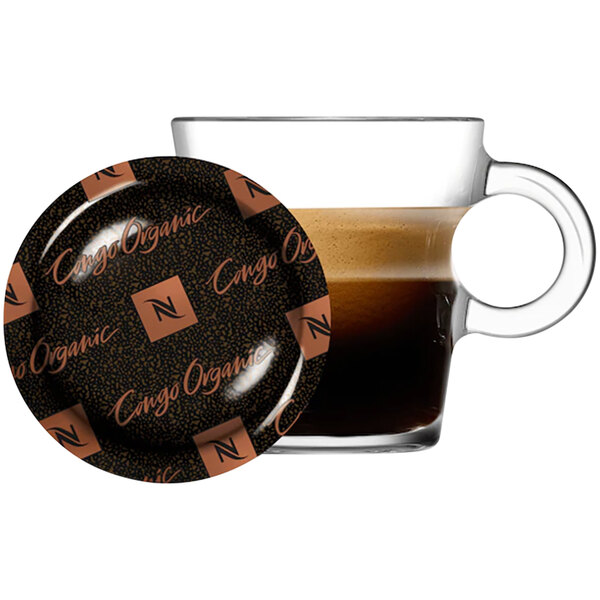 A glass cup of Nespresso Congo coffee with a saucer and plate on the side.