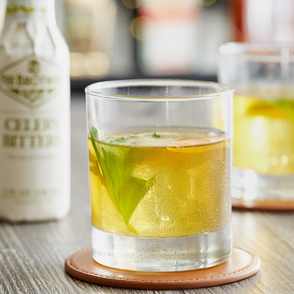 A glass of drink with Fee Brothers Celery Bitters on a table.