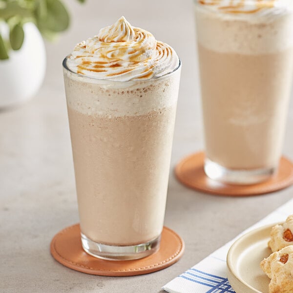 Two glasses of Frozen Bean caramel latte with whipped cream and caramel topping.
