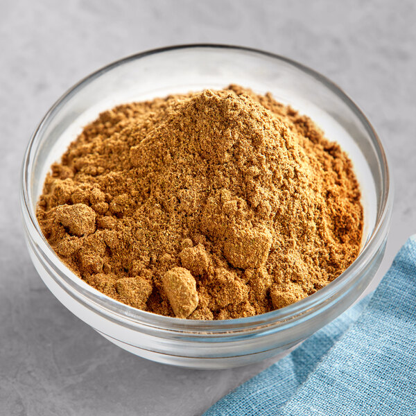 A bowl of brown Regal Garam Masala on a table with a blue cloth.