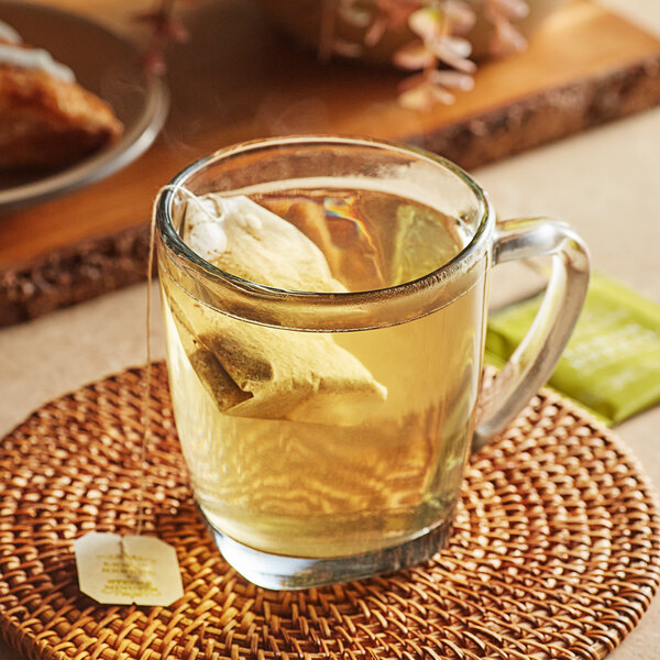 A glass mug of Harney & Sons Lemon Herbal tea with a tea bag in it.