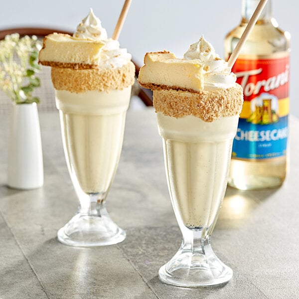 Two glasses of cheesecake-flavored desserts with Torani Cheesecake syrup on top.