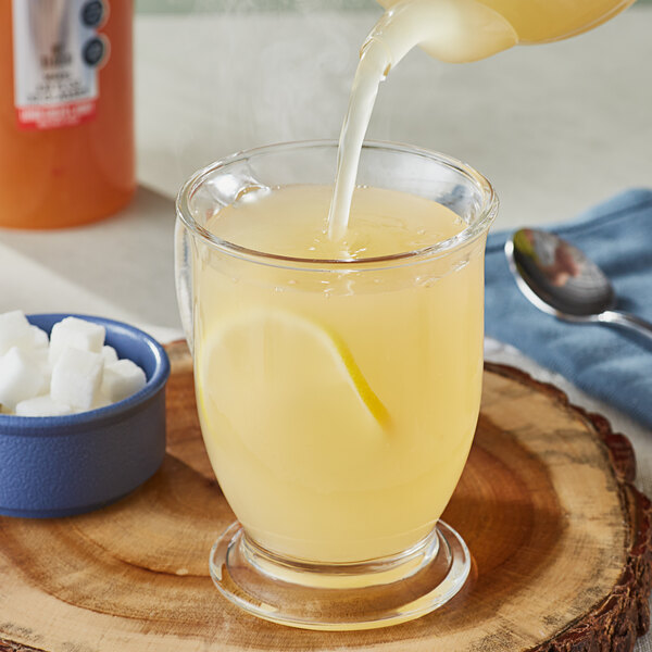 A person pouring SHOTT Lemon syrup into a glass of liquid.