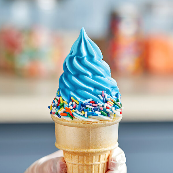 A hand holding a large ice cream cone with Phillips blue ice cream shell coating and blue sprinkles.