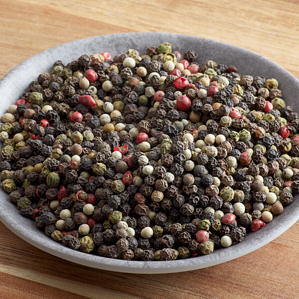 A bowl of Regal Gourmet Peppercorn Medley on a wood table.