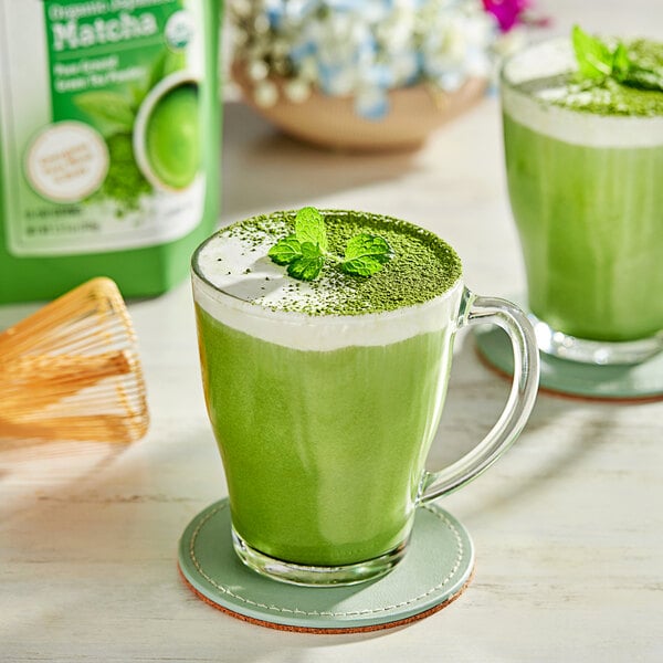 A green drink in a glass with Twinings Organic Matcha Tea Powder on top.