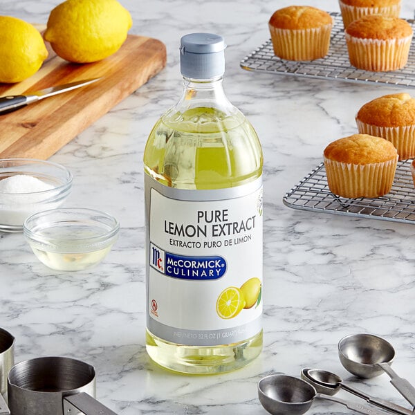 A bottle of McCormick Culinary lemon extract on a counter next to muffins.