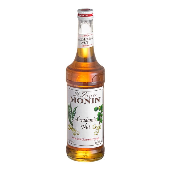 A Monin bottle of Macadamia Nut flavoring syrup with a white label.