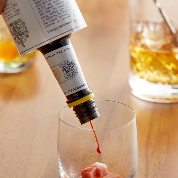 A bottle of Angostura aromatic bitters being poured into a glass.