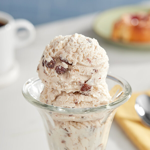 A glass bowl filled with a scoop of white rice rum raisin ice cream.