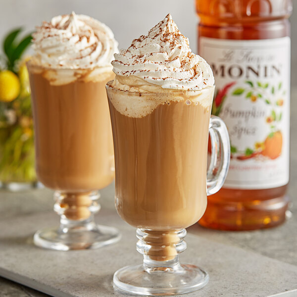 Two glasses of coffee with whipped cream and Monin Pumpkin Spice syrup.