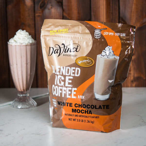 A bag of DaVinci Gourmet White Chocolate Mocha coffee mix next to a cup of blended ice beverage.