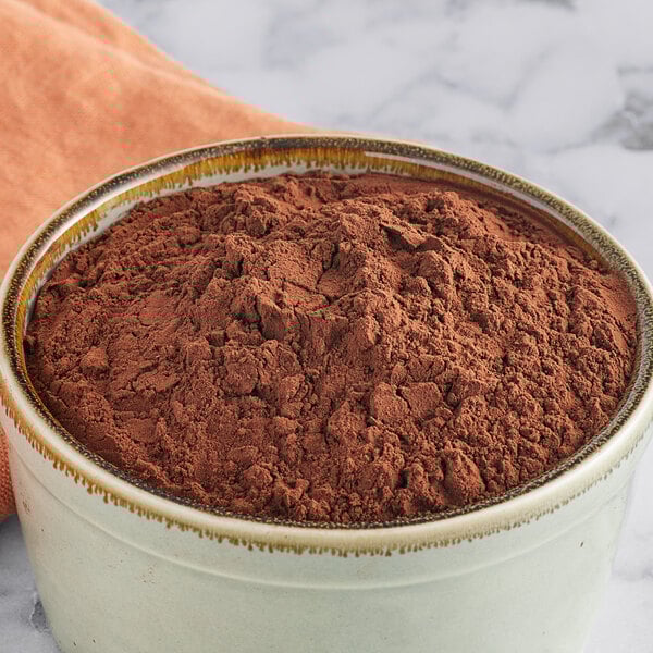 A bowl of Cacao Barry Extra Brute cocoa powder on a marble counter.