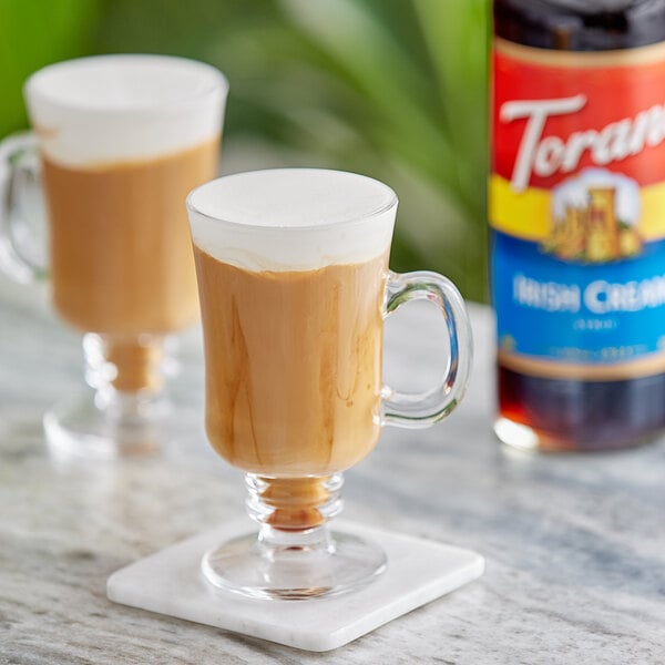 Two glass mugs of Irish coffee with Torani Irish Cream syrup.