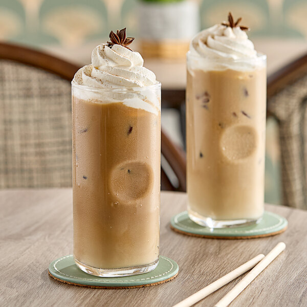 Two glasses of brown Dr. Smoothie Vanilla Chai with whipped cream on top.