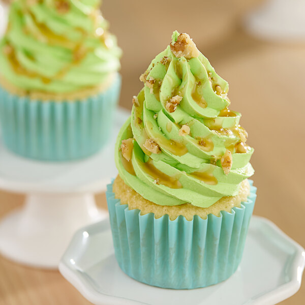A white plate with a cupcake with green Monin Granny Smith apple frosting and nuts.