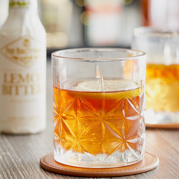 A glass of whiskey with Fee Brothers Lemon Bitters on a coaster.